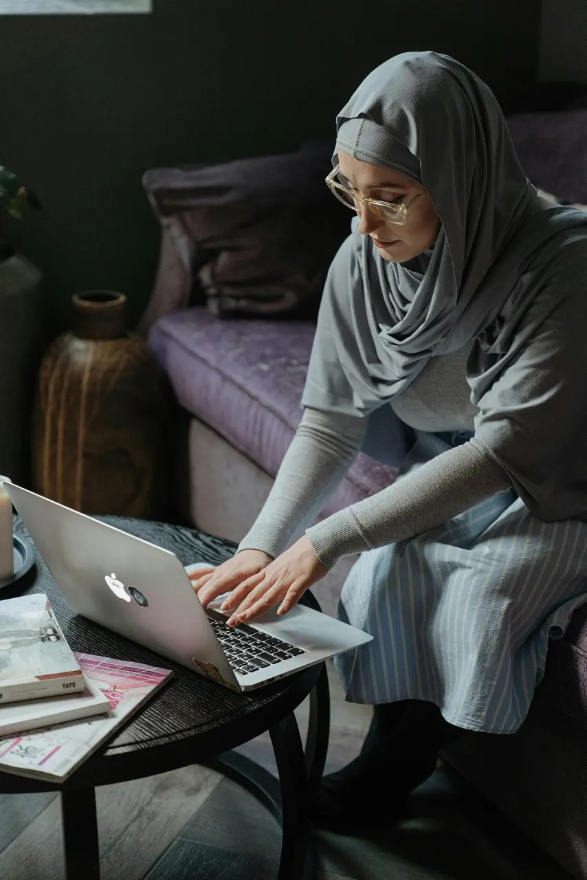 A woman using a laptop from a sofa at home