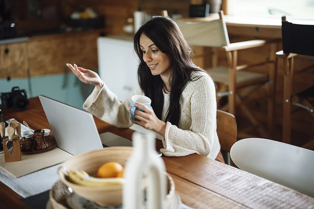 A woman talking beside an open laptop